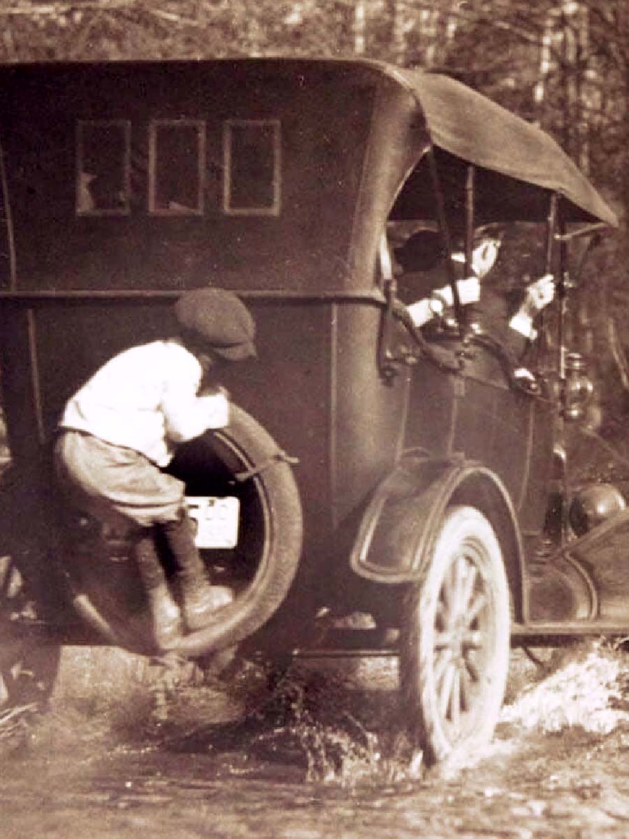 Boy catching a ride on the back of a Model T Ford